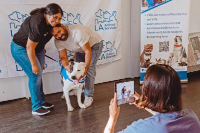 Person taking a photo of a couple with a dog going out on Adventure Buddy Day