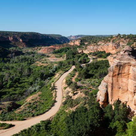 Road running through red rock canyon with blue sky