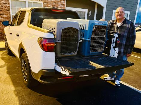 Jim Hess beside some carriers in the back of a pickup truck