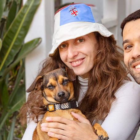 Couple holding a small dog sitting beside some plants
