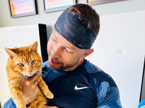 Catman holding an orange tabby cat