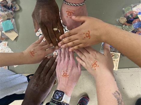 A group of human hands wearing Best Friends logo temporary tattoos all together in a circle