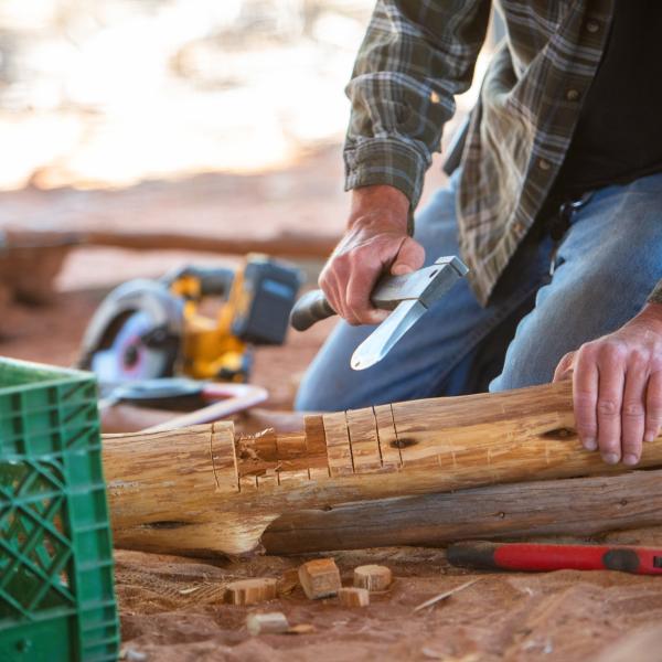 Person cutting a wooden log with an ax to create an enrichment item for Wild Friends
