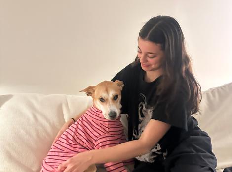 Eloise the dog wearing a striped T-shirt being hugged by Lauren