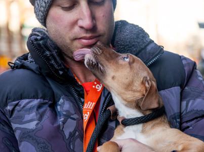Man smiling at a dog licking his face