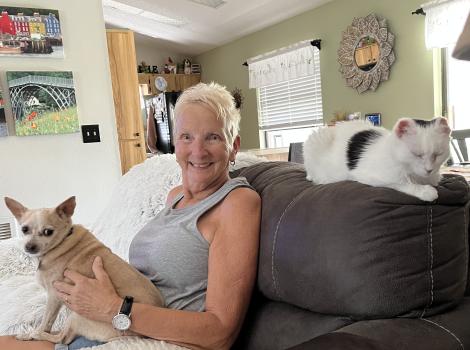 Frankie the cat on the back of the couch next to Judy Reynolds and a small dog