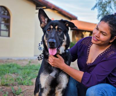 Smiling person kneeling next to a dog outside a pet adoption center in Los Angeles