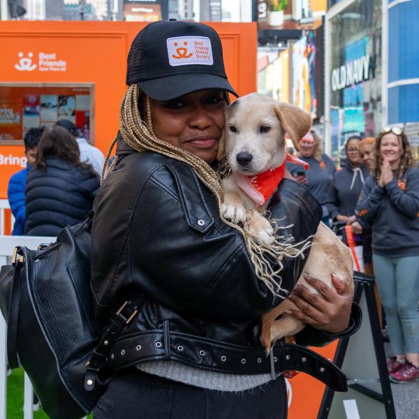 Persona con una gorra de Best Friends cargando a un cachorro