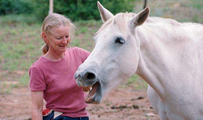 Best Friends Animal Society co-founder Diana Asher outside with a white horse whose mouth is open
