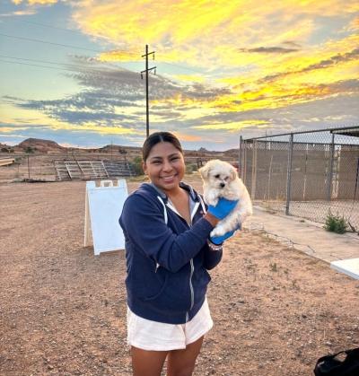 Person smiling and holding a small dog at the Navajo Nation during a sunrise or sunset