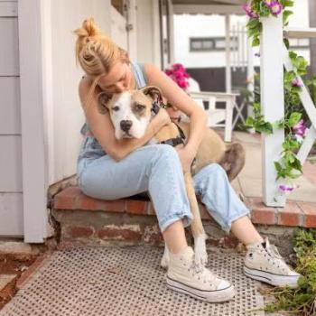 Person sitting on patio steps while hugging a dog