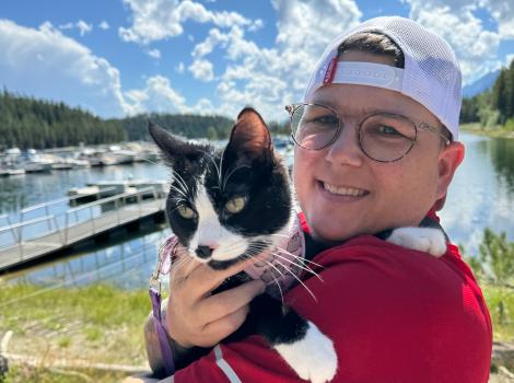 Lisa holding McMuffin the cat outside in front of a blue sky with clouds
