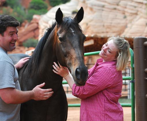 Two smiling people standing outside with a horse at Best Friends Animal Sanctuary