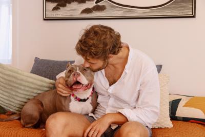Person with his arm around a dog while kissing the dog's head