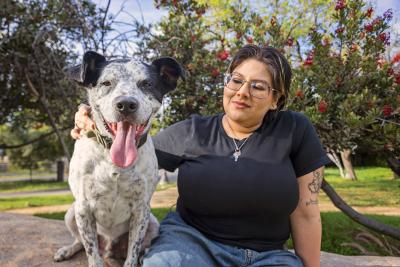 Person sitting outside with a large black and white dog whose tongue is out