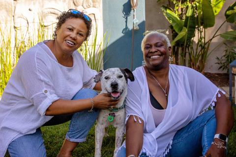 Two people with a dog smiling at the camera