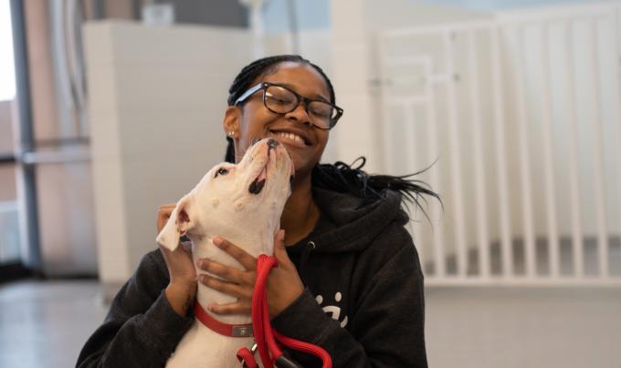 Smiling person getting kissed on the face by a dog