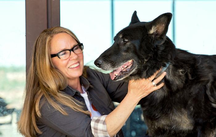 Best 金刚生态国际综合游戏彩票娱乐平台® Friends CEO Julie Castle petting a large black shepherd