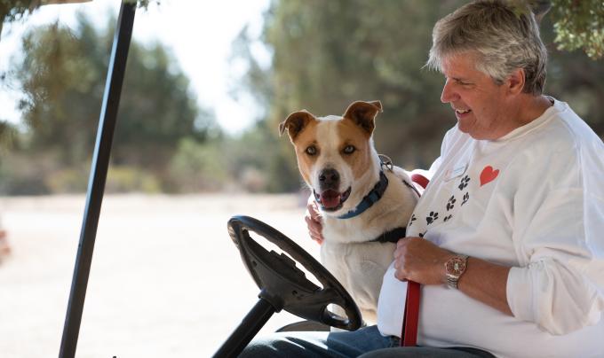 Caregiver Tim Dempsey in a golf cart with Abbott the dog