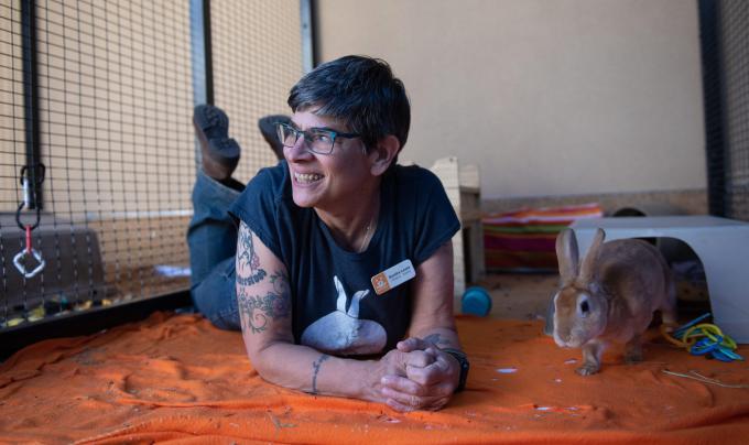 Caregiver Sondra Lewis smiling while lying next to Binky the rabbit