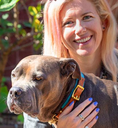 Person hugging a dog while sitting in a sunny garden